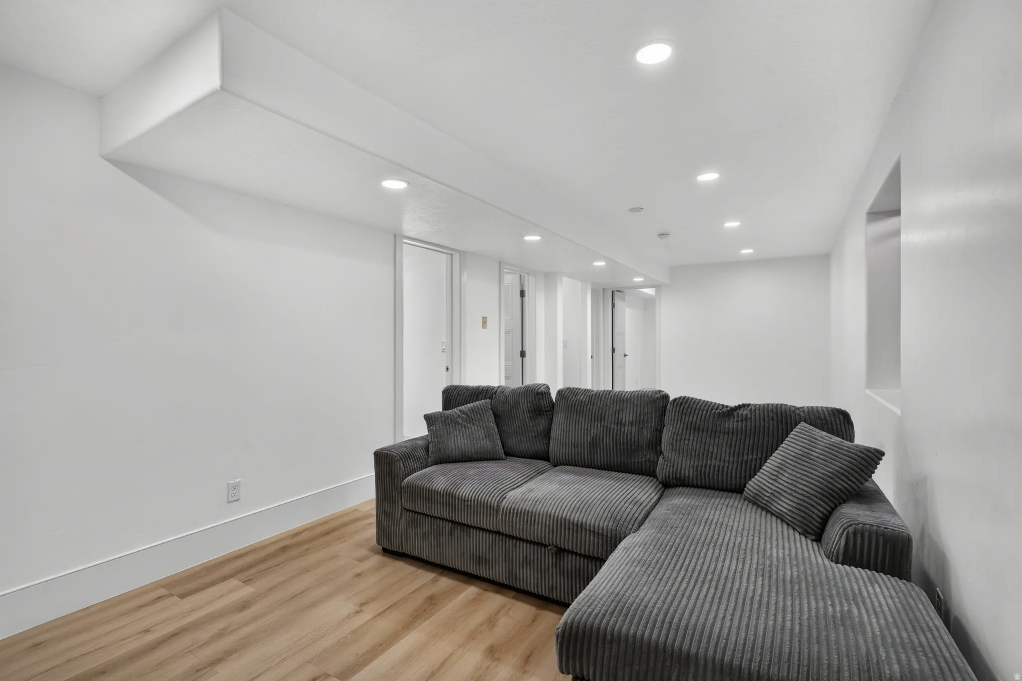 Spacious room featuring light wood-finish flooring, recessed lighting, and a white color palette