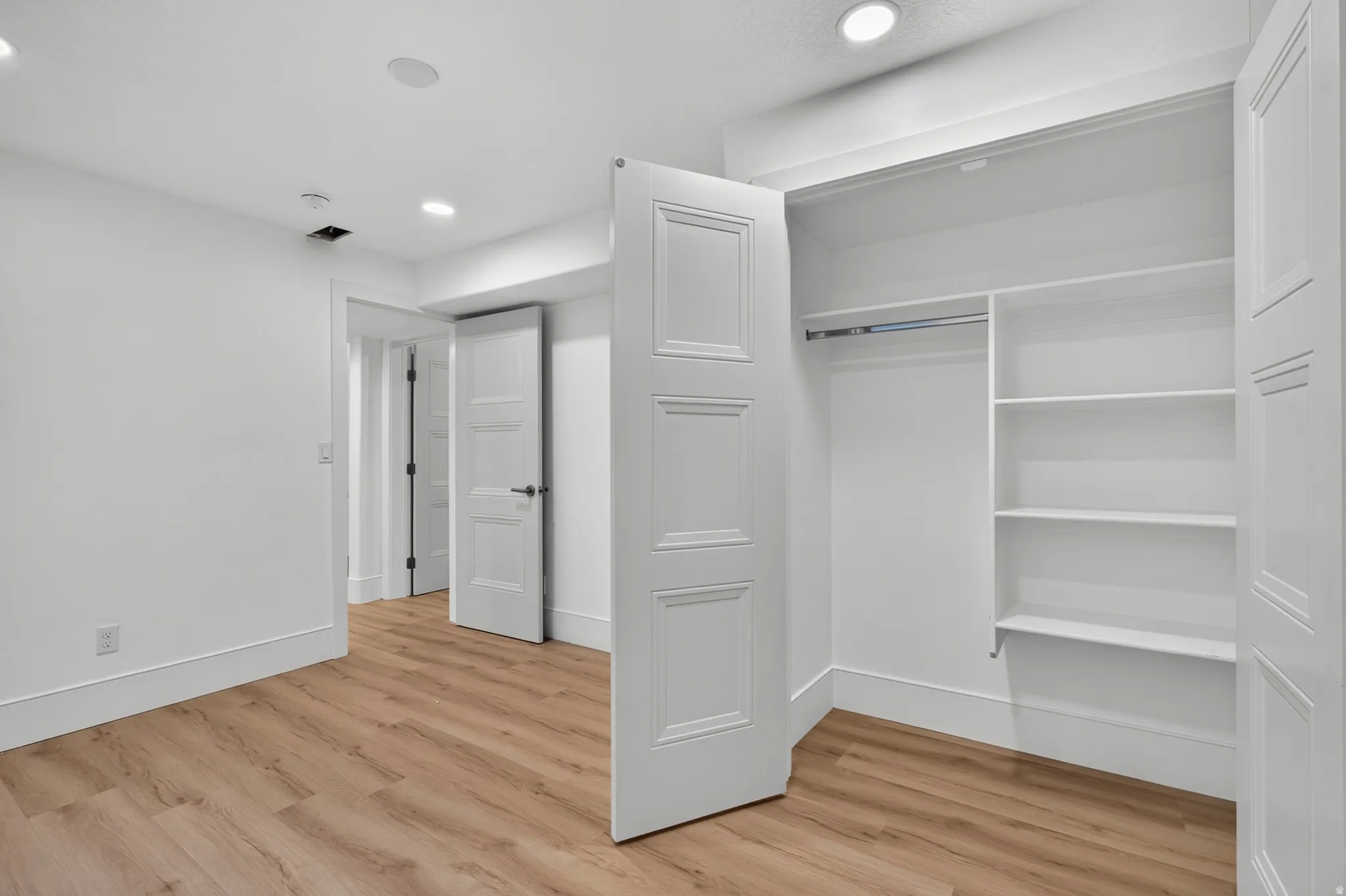 Bedroom featuring wood-finish flooring, white baseboards, and bright white walls
