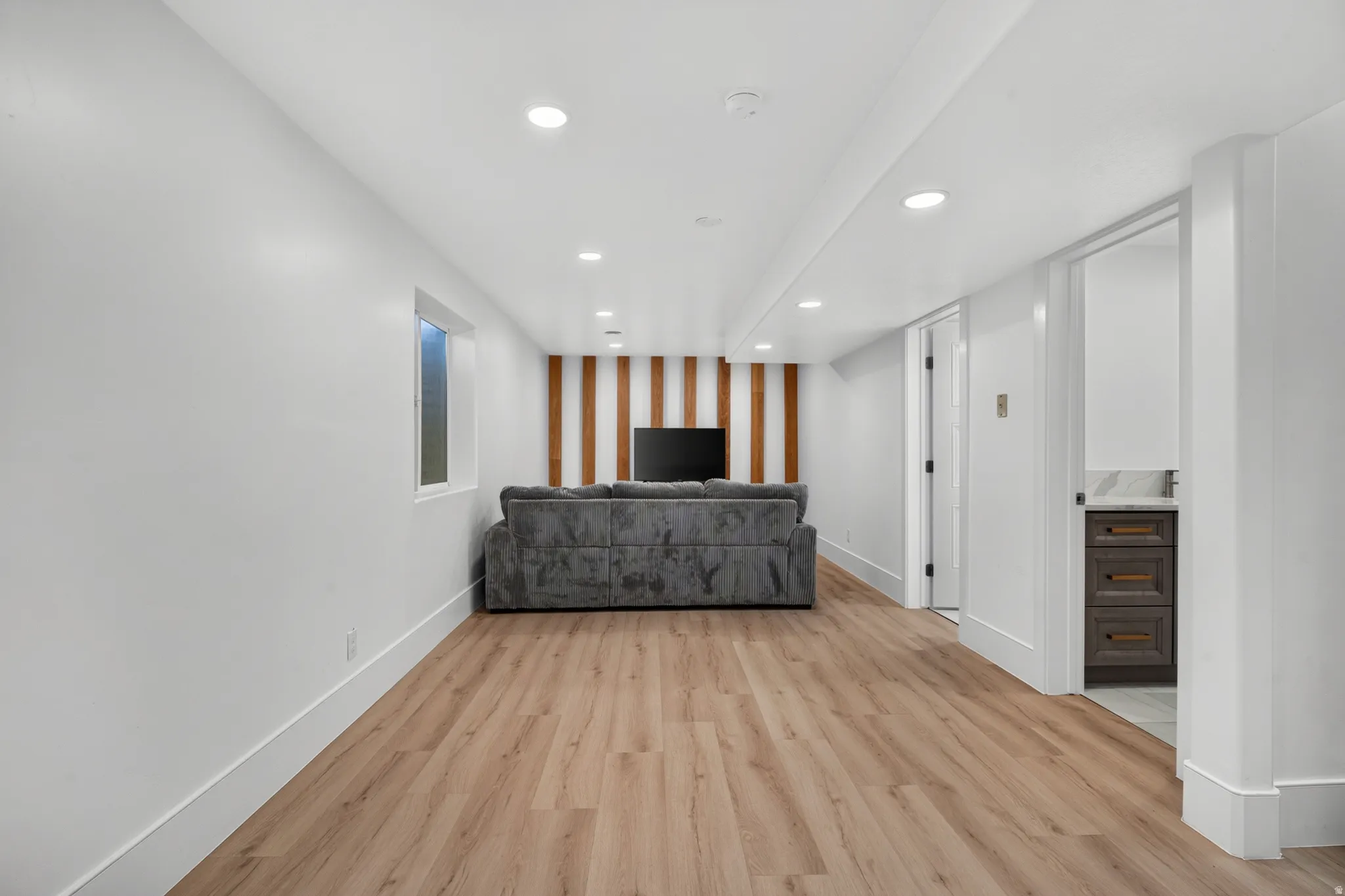Spacious room featuring wood-finish flooring, recessed lighting, and a window