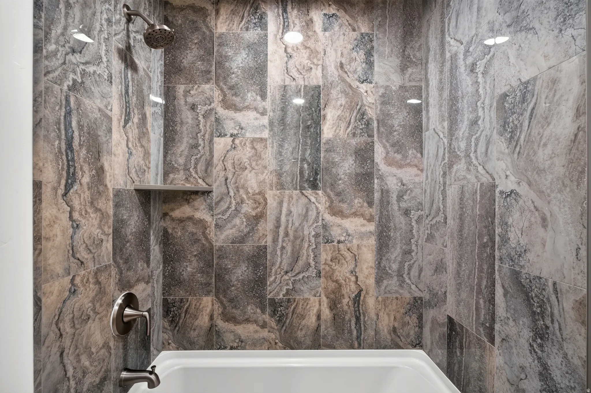 Bathtub and shower combination featuring floor-to-ceiling multi-tonal tiled walls