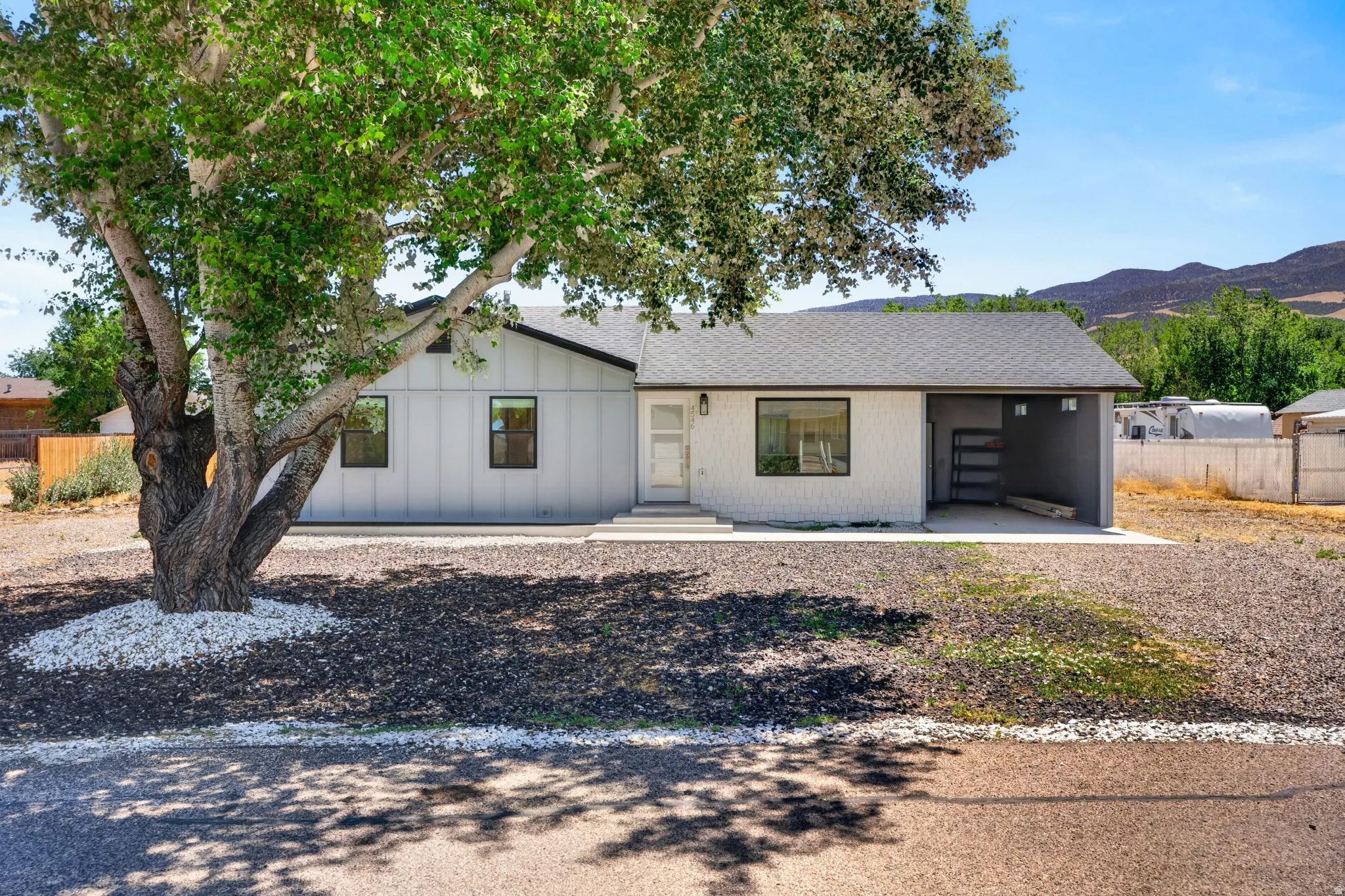 Contemporary ranch-style exterior with a dark gray shingle roof and a light gray vertical siding accent
