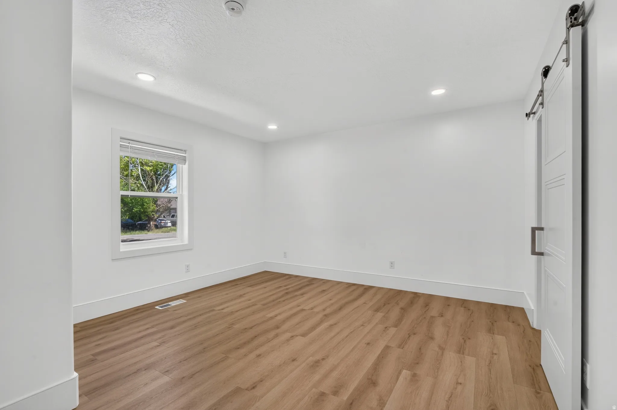 Bright room featuring wood-finish flooring and recessed lighting