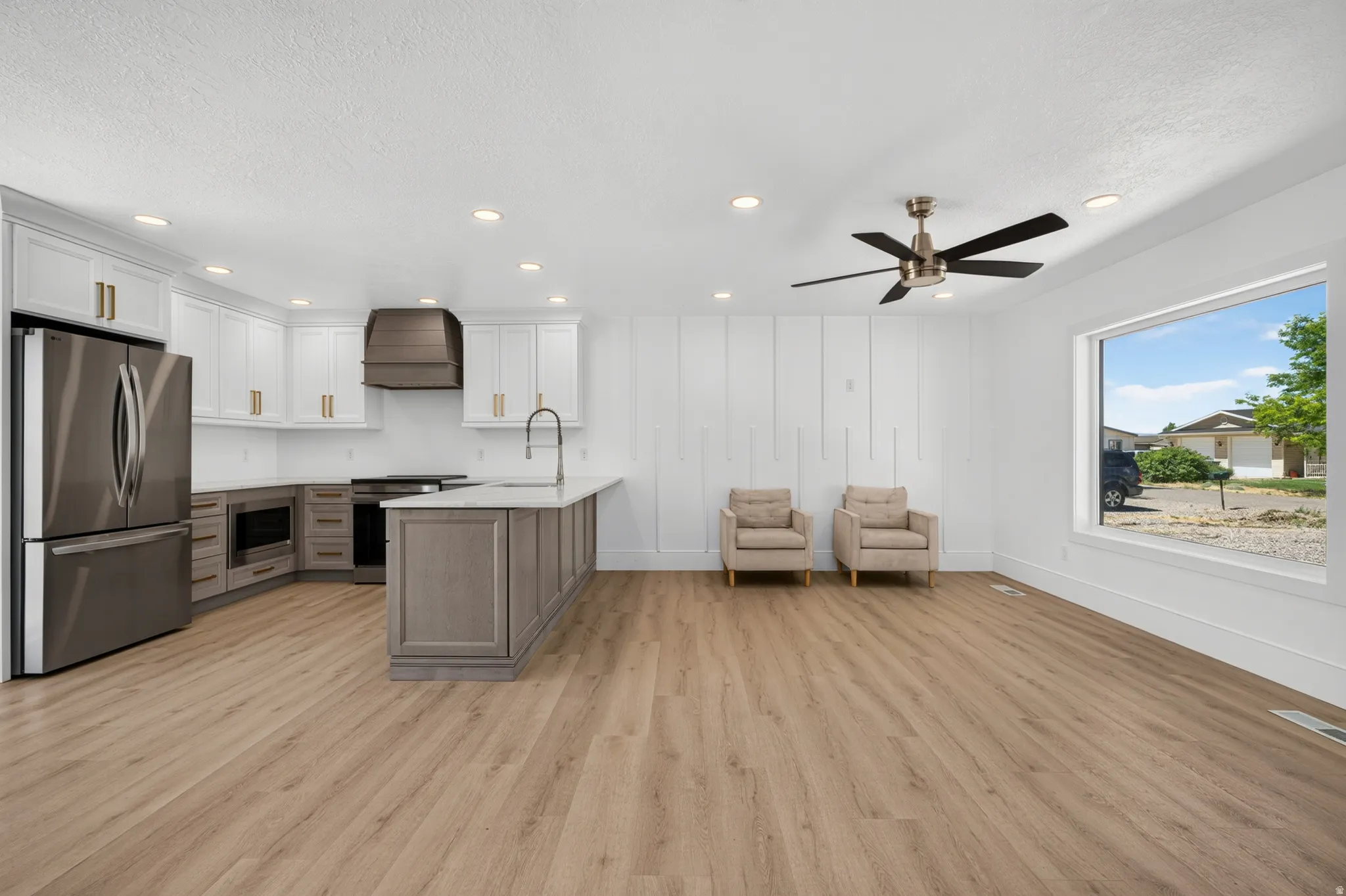Open-concept living space featuring wood-finish flooring, a contemporary ceiling fan, and a large window