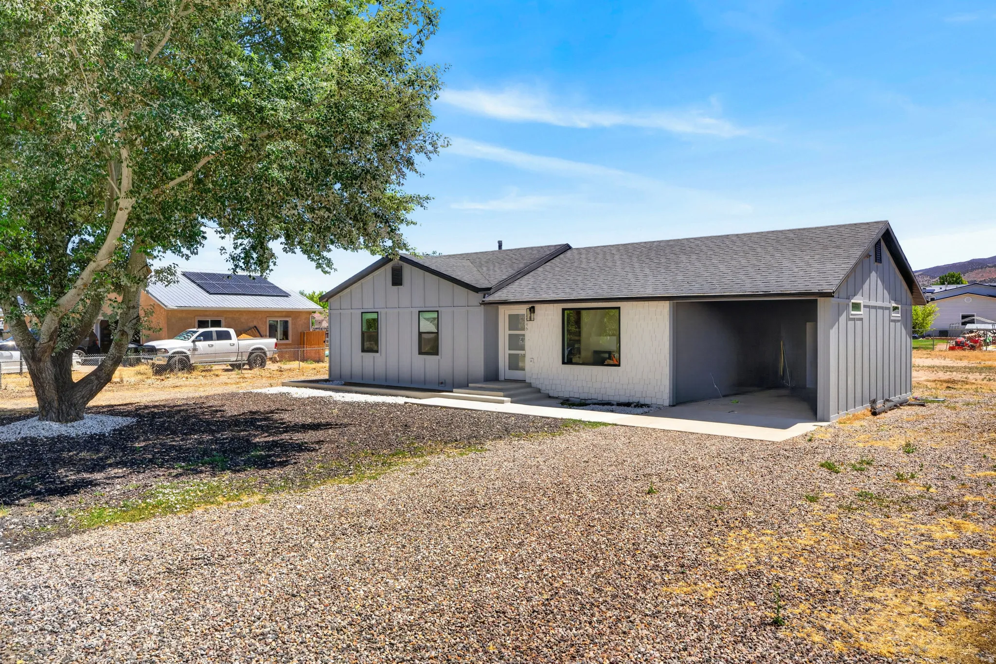 Contemporary exterior with a dark gray shingle roof, white textured siding, and a covered carport