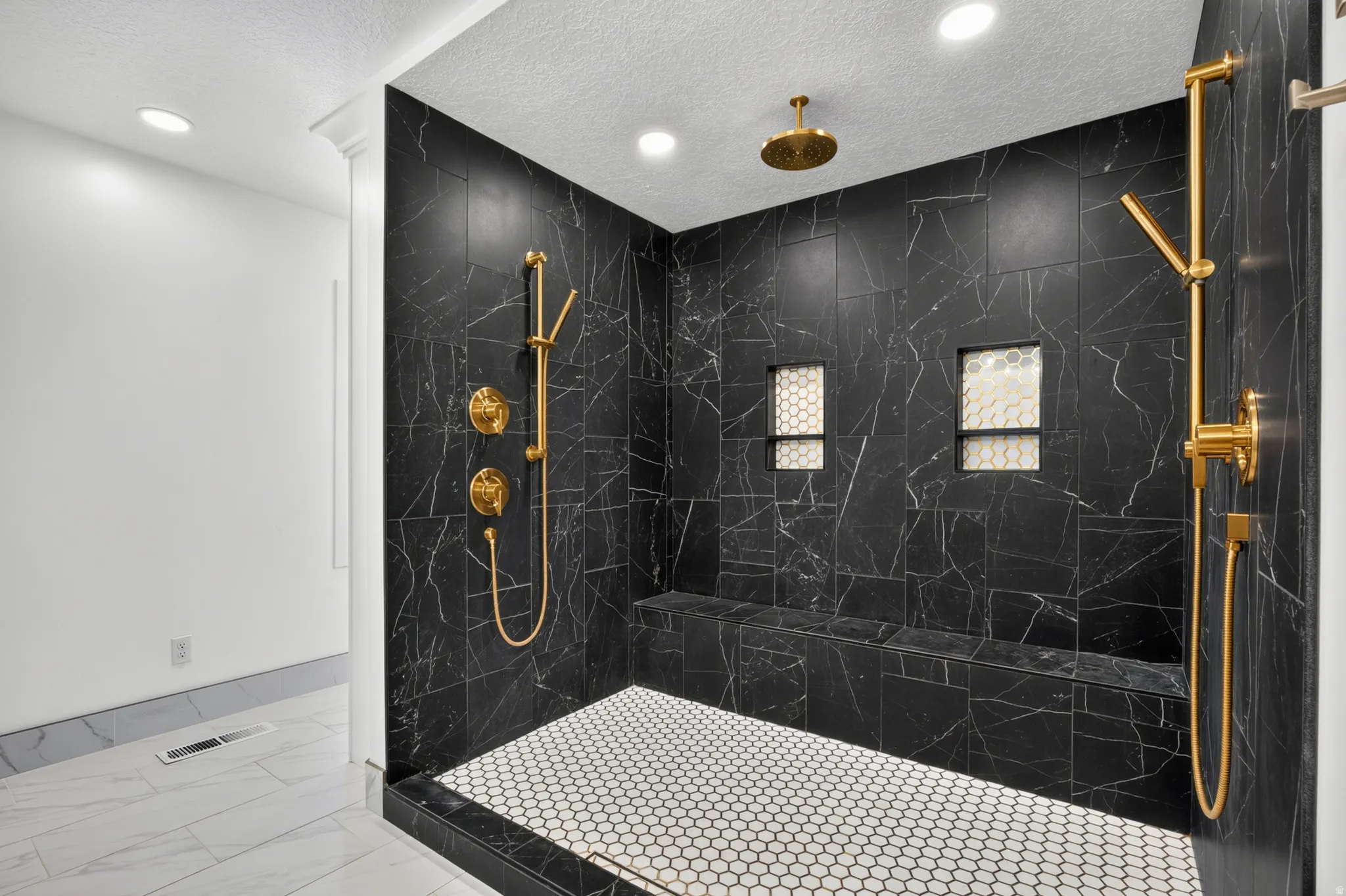 Walk-in shower featuring black marbled tile walls and gold-finish fixtures