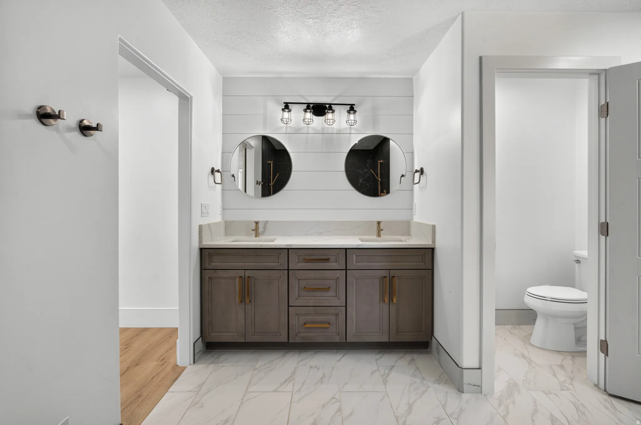 Dual vanity with a white shiplap accent wall, quartz countertop, and integrated sinks