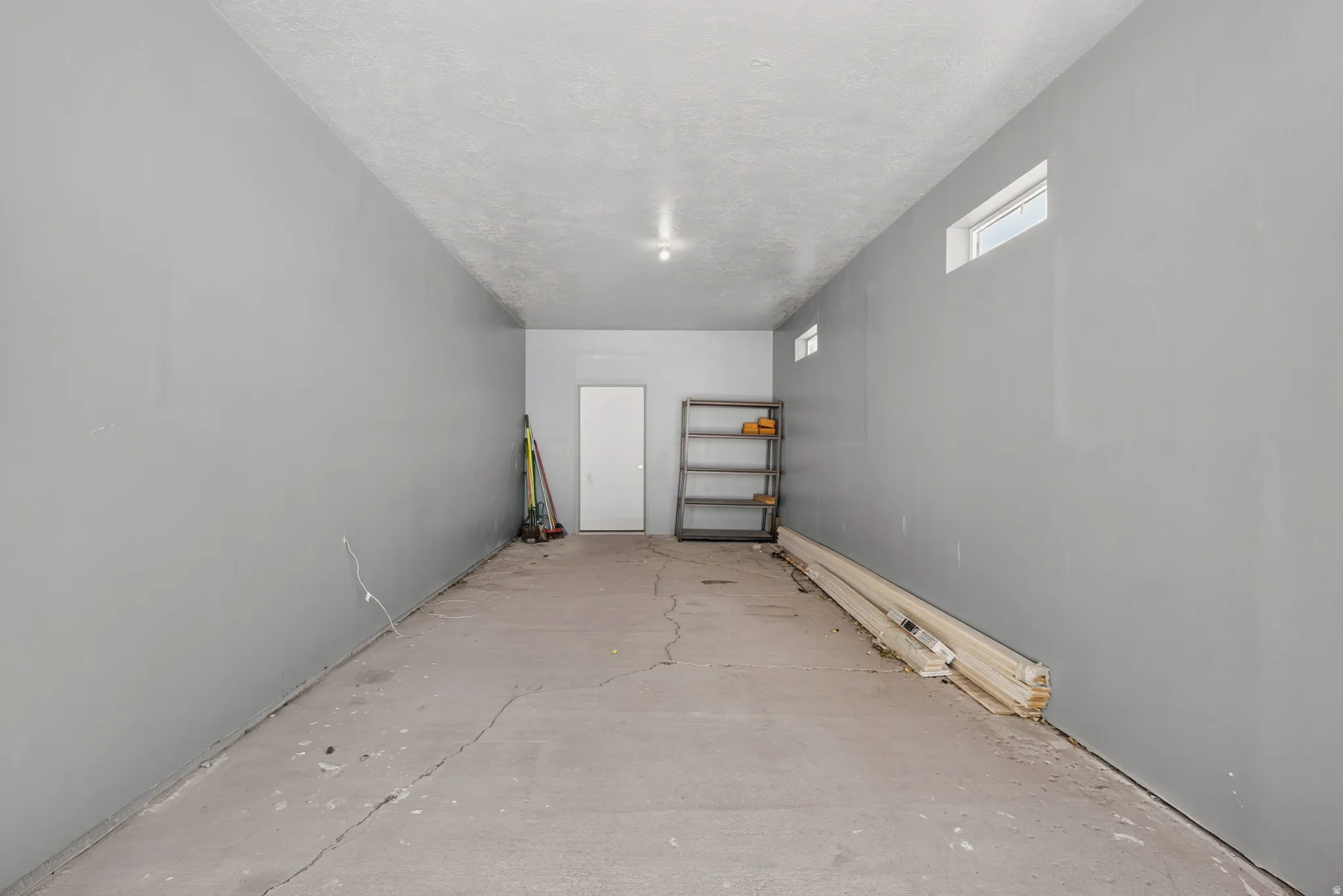 Spacious utility room featuring a concrete floor, light gray painted walls, and high-set windows
