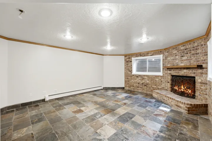 Spacious room featuring a corner brick fireplace with a decorative screen