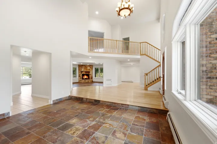 Two-story foyer featuring natural stone tile flooring, a hardwood staircase with wood railings, a multi-level layout, and an upper-level balcony