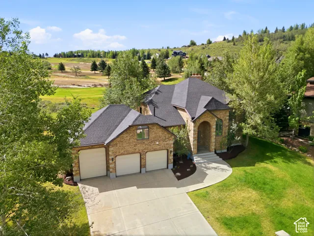 Brick and stone exterior with a multi-car garage, arched entryway, and dark shingle roofing