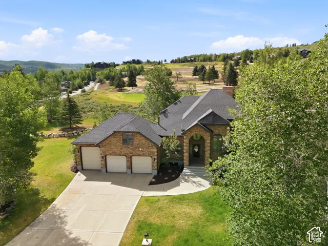 Stone facade, asphalt shingle roof, arched entryway, paved driveway, three-car garage