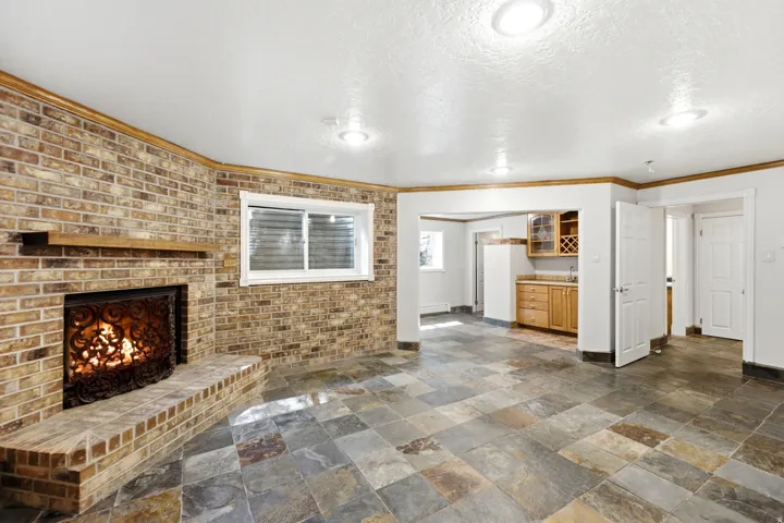 Brick accent wall featuring a wood-mantle fireplace
