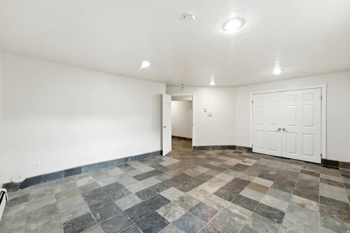 Spacious room featuring multi-toned slate tile flooring, white walls, and a recessed lighting system