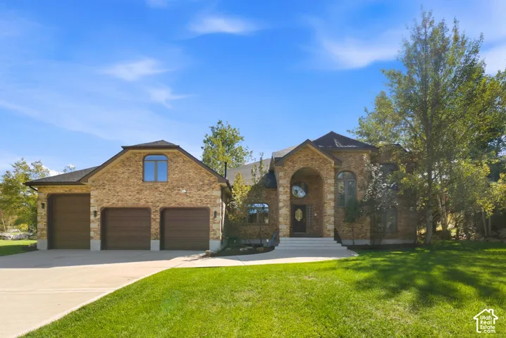 Stone facade with arched entry, arched windows, and a three-car garage