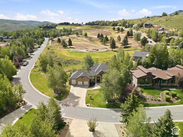 Stone and stucco exterior with a multi-level roofline, a paved driveway, and mature landscaping