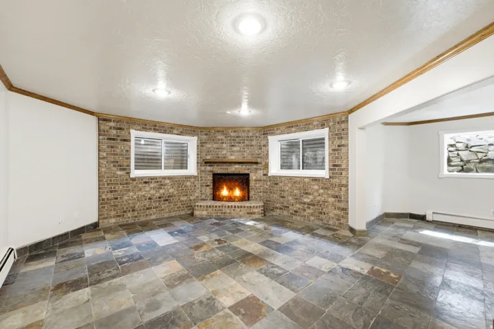 Spacious room featuring a brick fireplace, multi-toned slate tile flooring, and recessed lighting