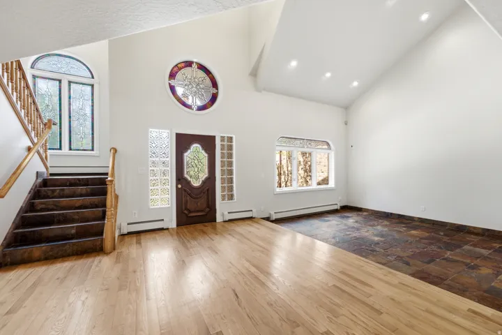 Grand entry foyer featuring a vaulted ceiling and a mix of hardwood and stone-finish flooring