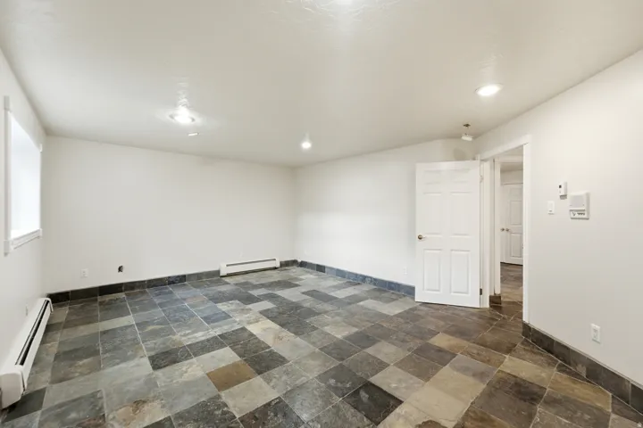 Spacious room featuring multi-tone slate tile flooring, white painted walls, and recessed ceiling lighting