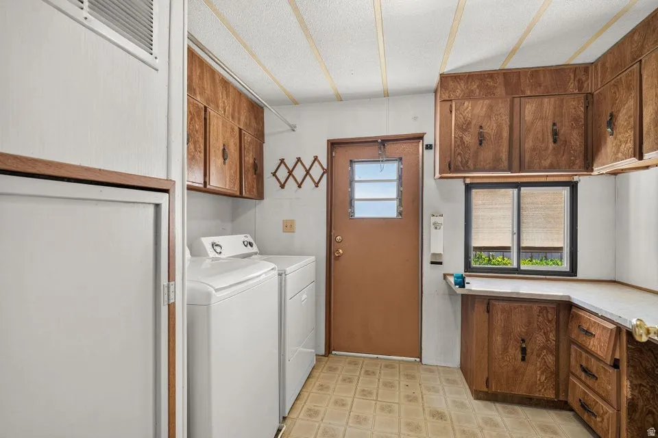 Utility space featuring extensive wood-finish cabinetry, a window with horizontal blinds, and a built-in countertop