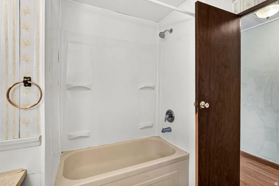 Alcove bathtub with an integrated shower, featuring a white surround and a dark bronze shower fixture