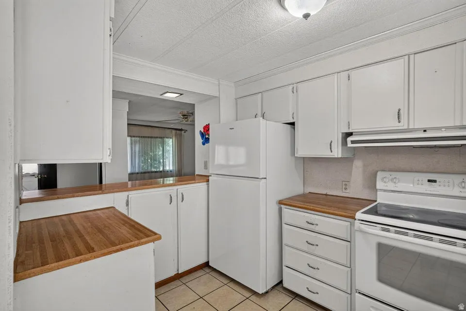 Kitchen featuring white cabinetry, wood-finish countertops, and tile flooring