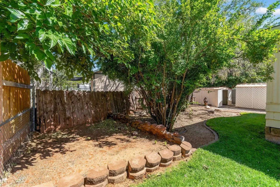 Private outdoor space featuring mature trees, a wood privacy fence, and a decorative block border