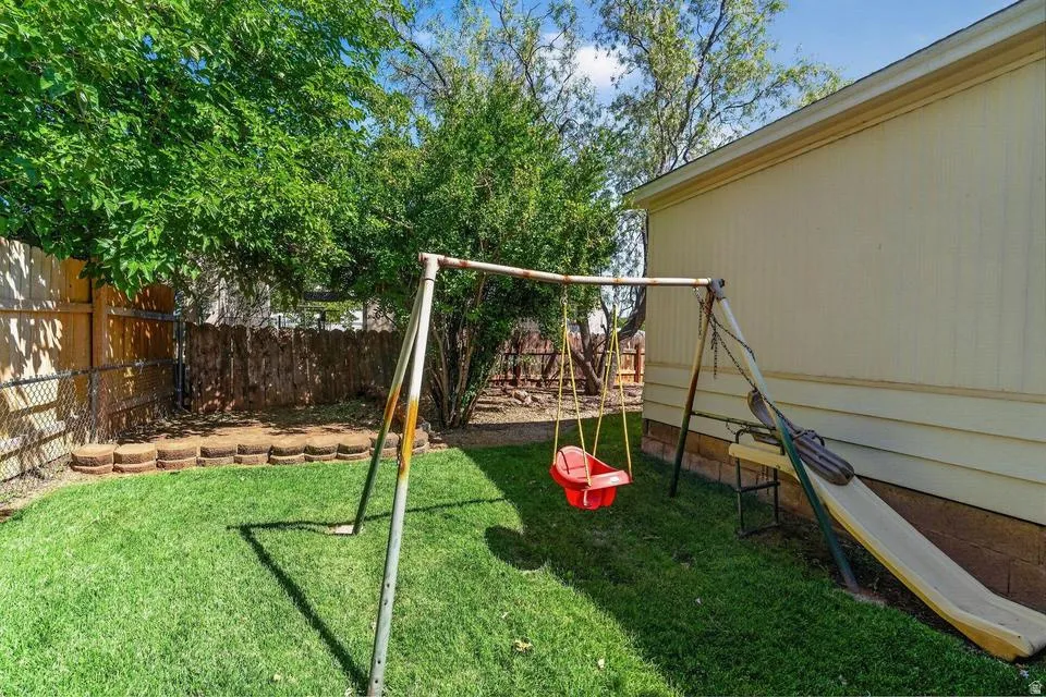 Expansive backyard featuring a manicured lawn, established trees, and a wooden privacy fence