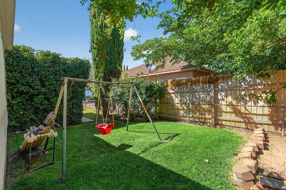 Expansive backyard featuring a manicured lawn, established trees, and perimeter fencing