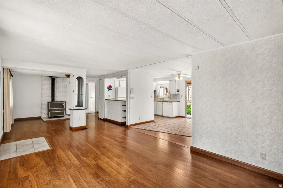 Spacious living area featuring wood-finish flooring, a white brick fireplace surround, and a built-in wood-burning stove