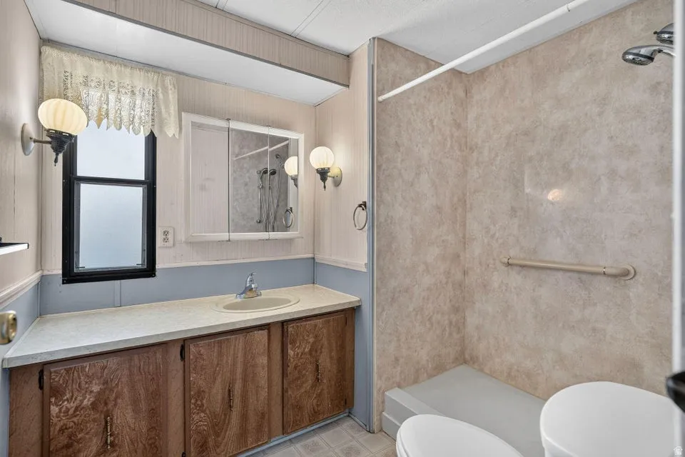 Bathroom featuring a walk-in shower with textured wall panels and a built-in grab bar