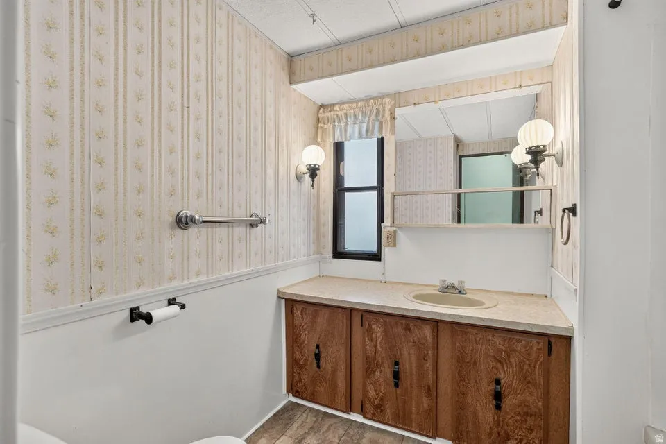 Bathroom featuring a vanity with a laminate countertop, a single basin sink, and wood-finish cabinetry