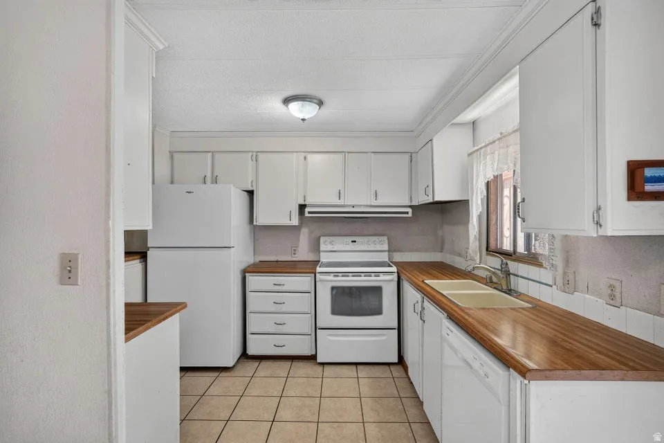 Kitchen featuring white cabinetry, wood-finish countertops, and a tile floor