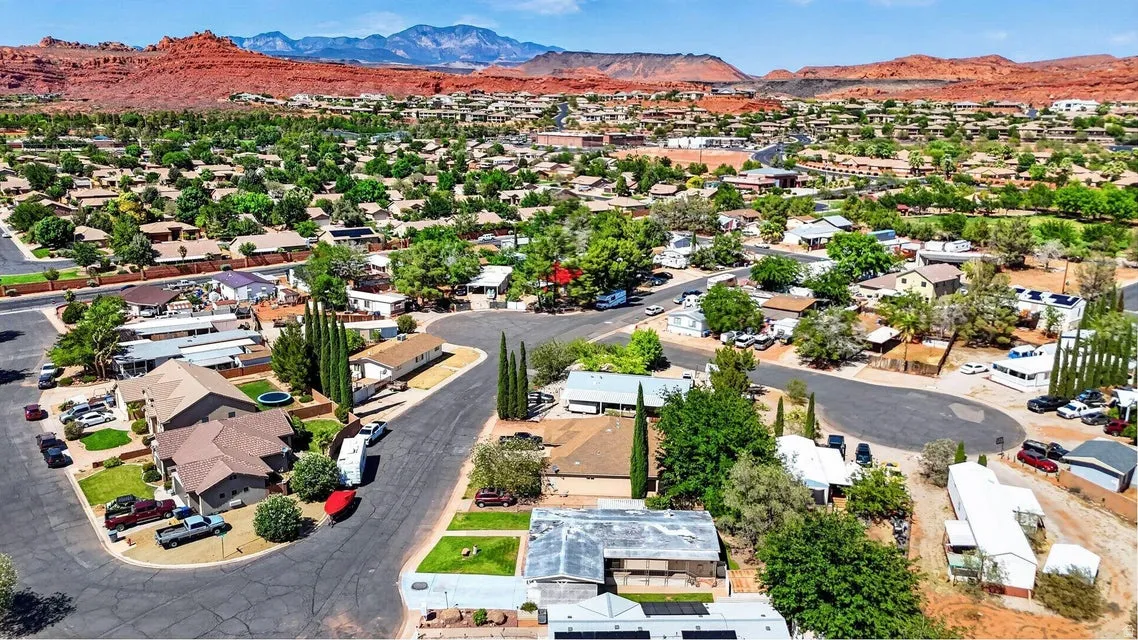 Residential neighborhood with mature trees, paved streets, and desert landscaping, set against a mountainous backdrop