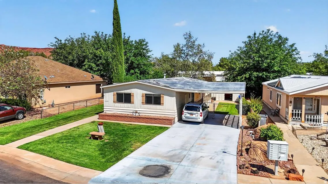 Single-story residence featuring light-colored siding, a covered carport, and a concrete driveway