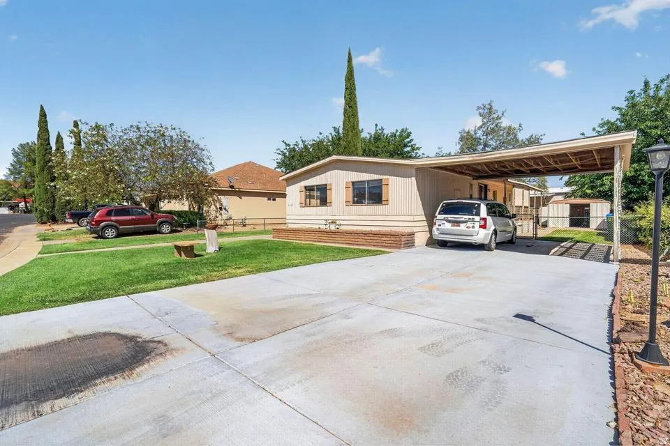 Single-story residence featuring a carport, concrete driveway, and a manicured lawn