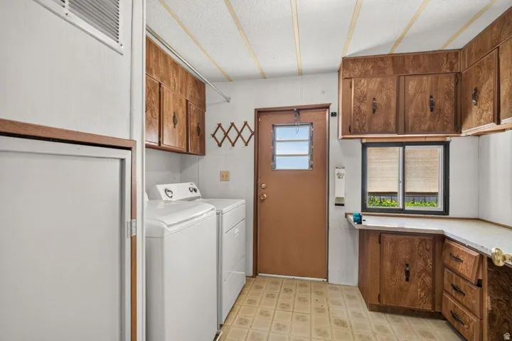 Utility space featuring extensive wood-finish cabinetry, a window with horizontal blinds, and a built-in countertop