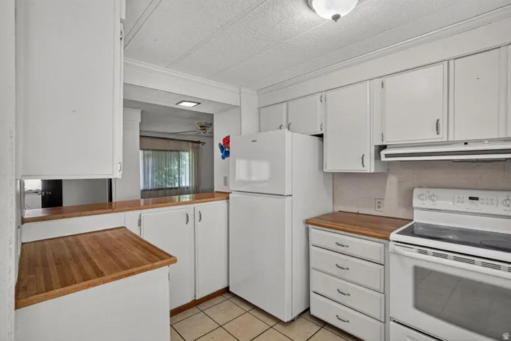 Kitchen featuring white cabinetry, wood-finish countertops, and tile flooring