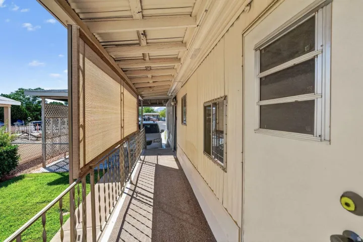 Covered porch featuring a metal railing, roll-down sunscreens, and a textured floor surface