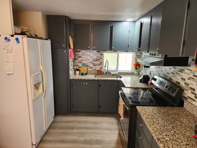 Kitchen featuring dark cabinetry, light-toned wood-finish flooring, and speckled countertops
