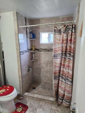 Tiled shower enclosure featuring a fixed window, decorative accent band, and integrated corner shelving
