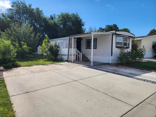 White manufactured home featuring a covered entry, bay window, and concrete driveway
