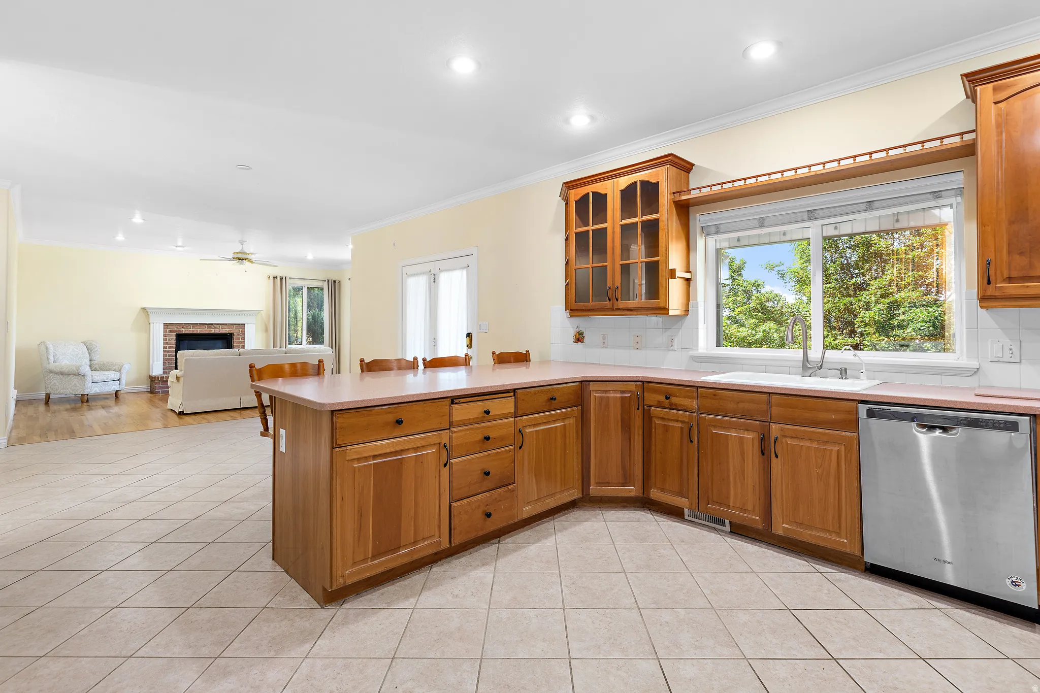 Kitchen featuring wood cabinetry, stainless steel dishwasher, and a large window above the sink