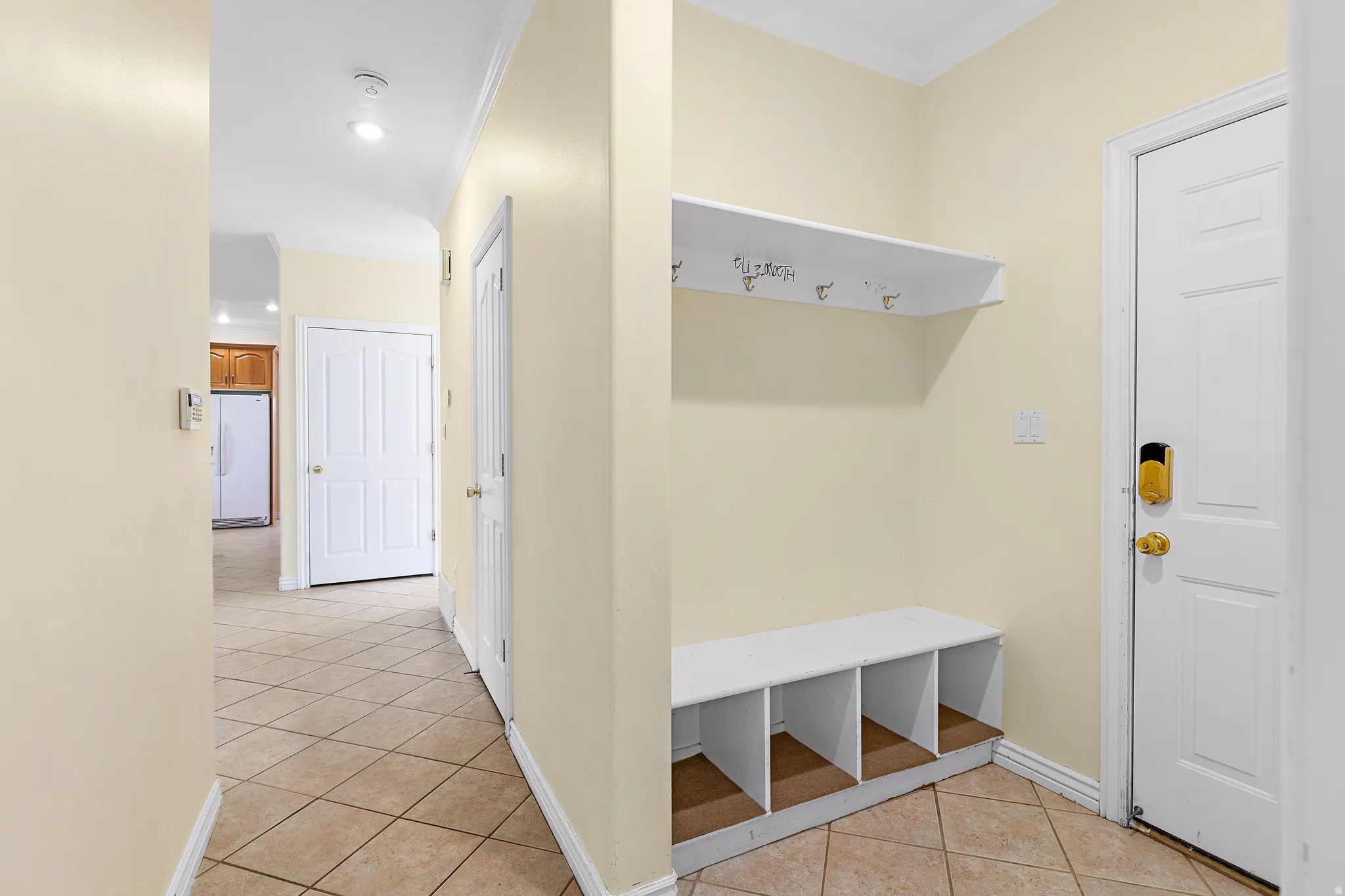 Entryway featuring a built-in bench with cubby storage, an overhead shelf with coat hooks, and durable tile flooring