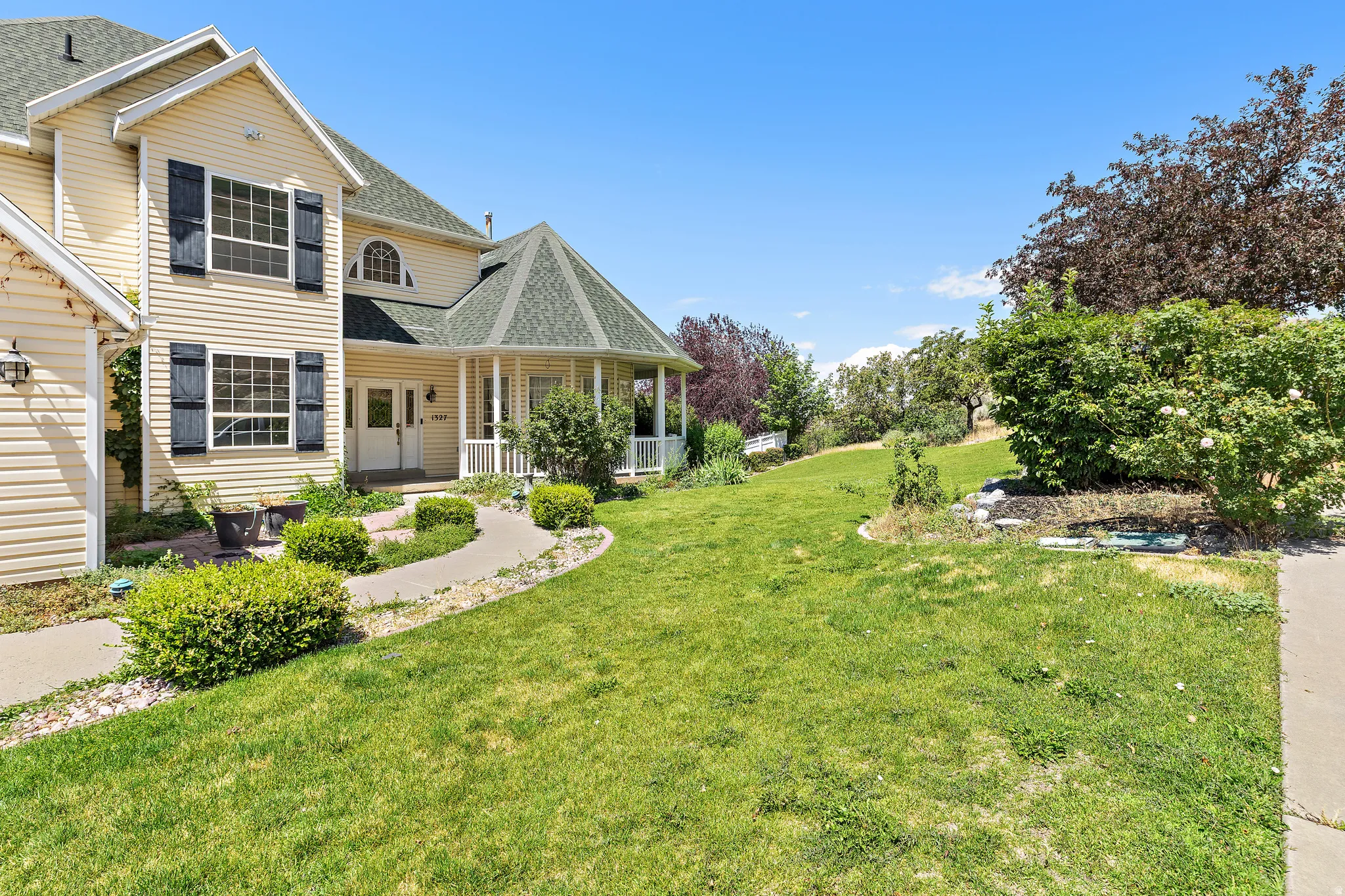 Expansive front yard with a curved concrete pathway and mature landscaping