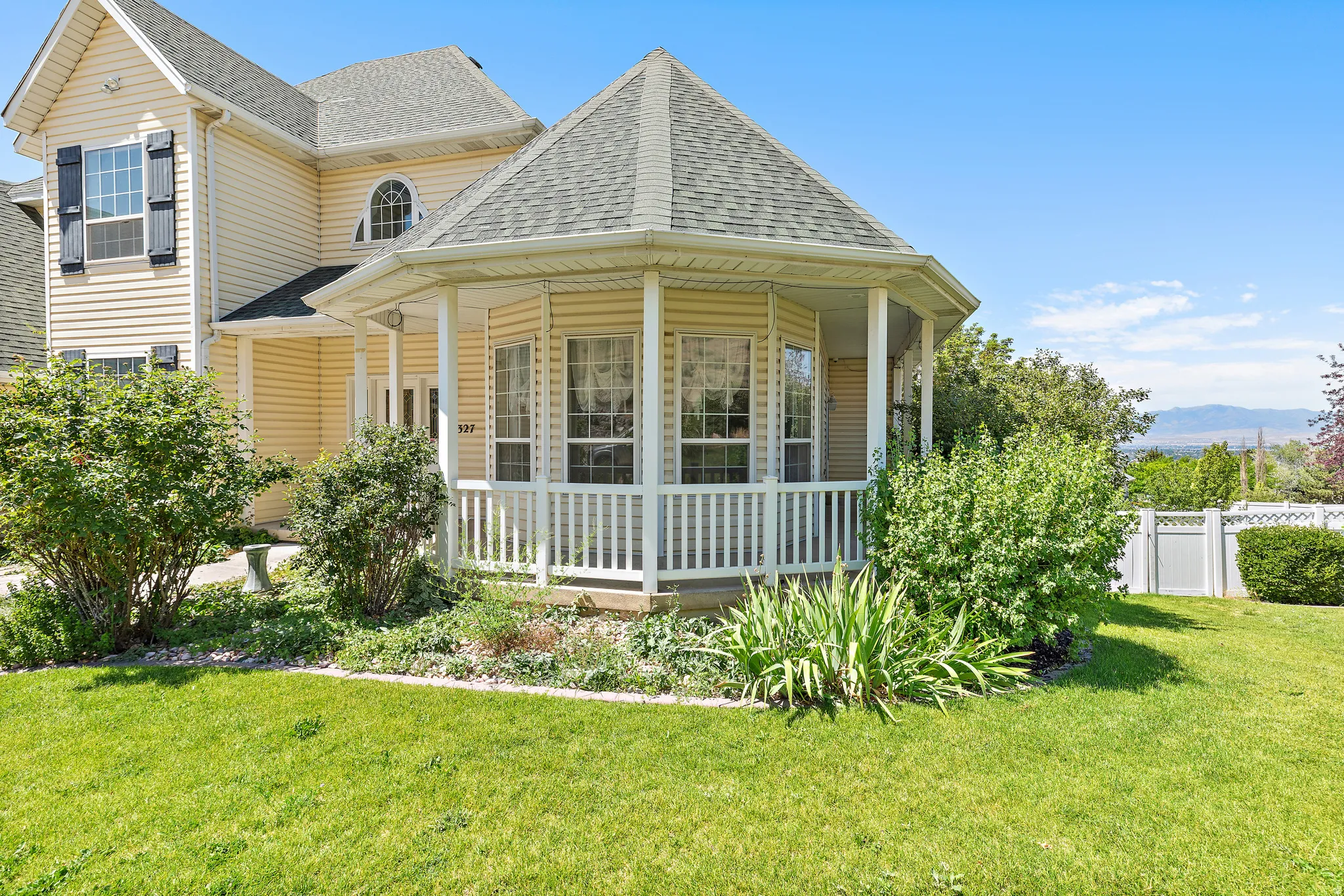 Exterior featuring light-colored siding, a covered polygonal porch with white railing, and multiple gabled rooflines