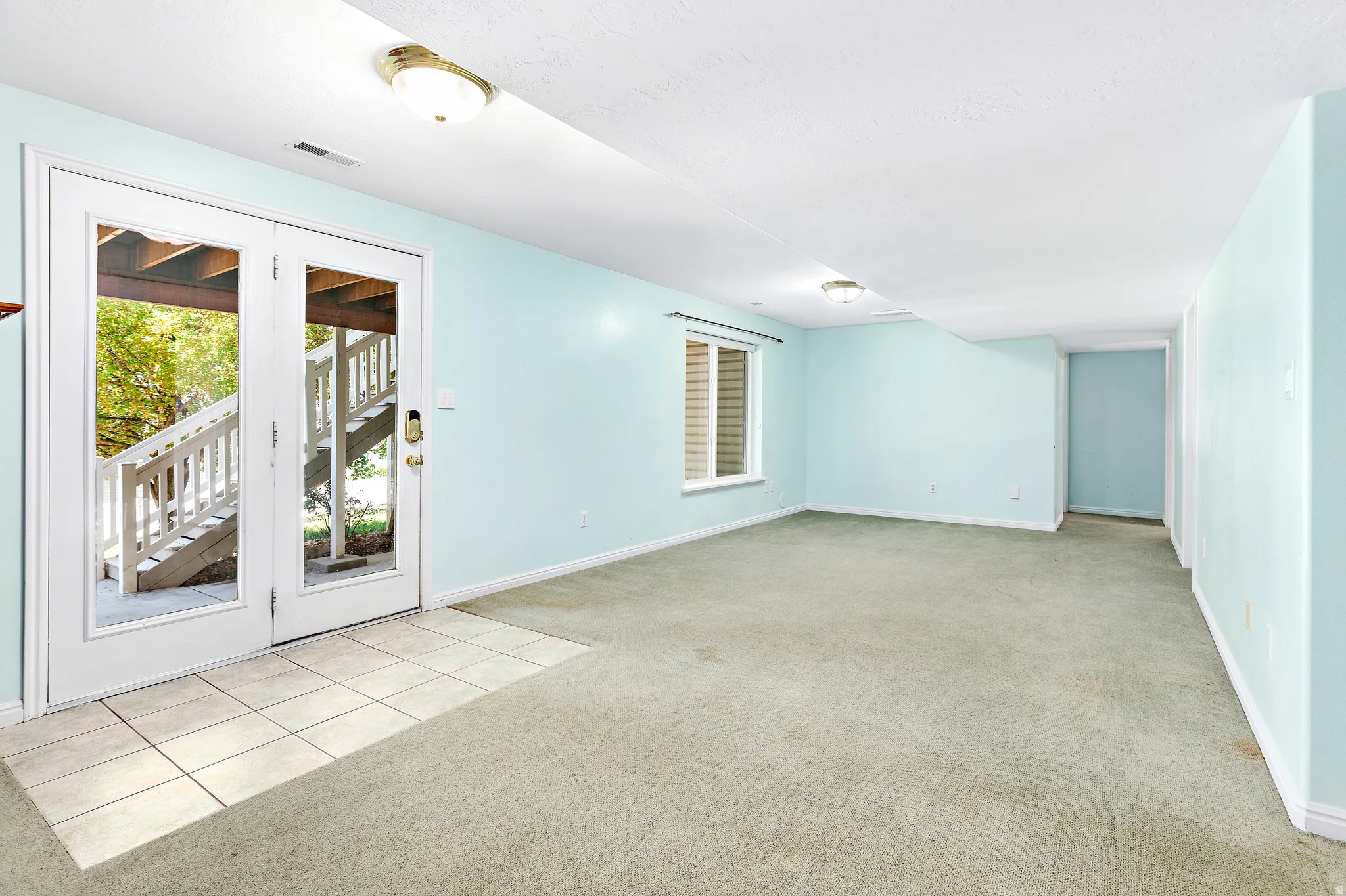 Spacious interior room featuring light blue walls, carpet flooring, and a white ceiling