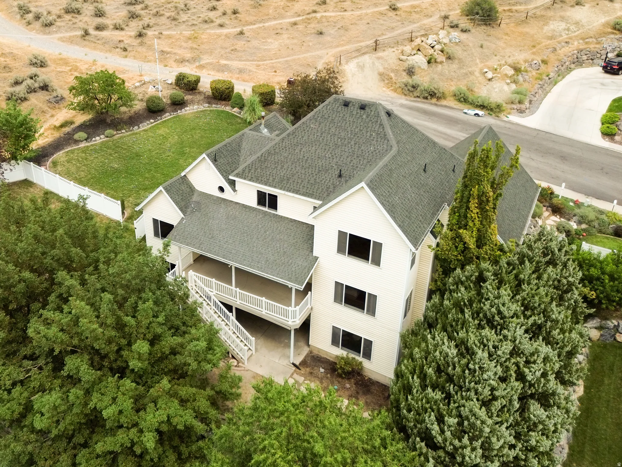 Multi-level residence featuring a covered balcony, white railing, and a gabled roof