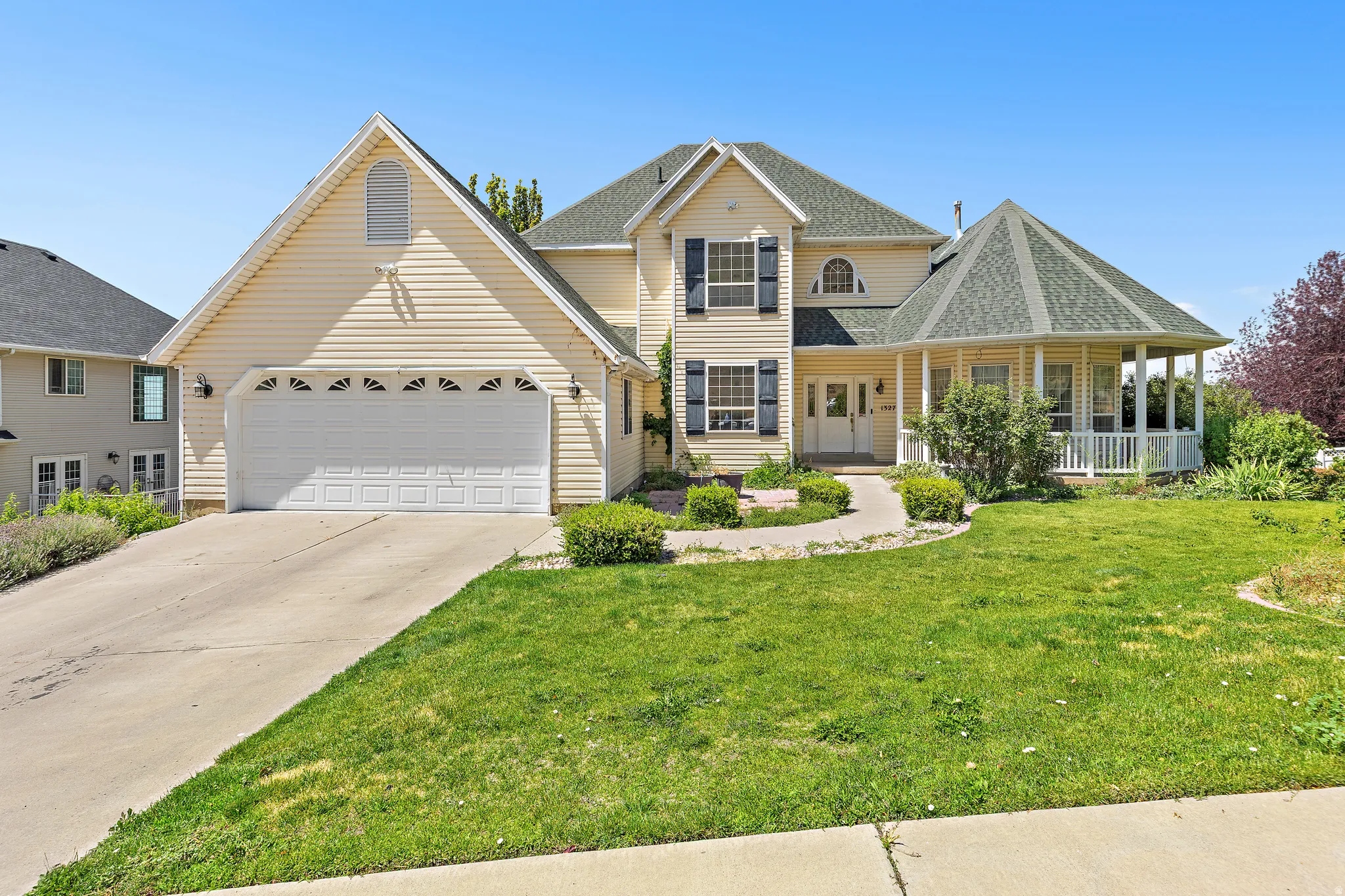 Light yellow siding exterior with a multi-gabled roofline and a prominent two-car garage