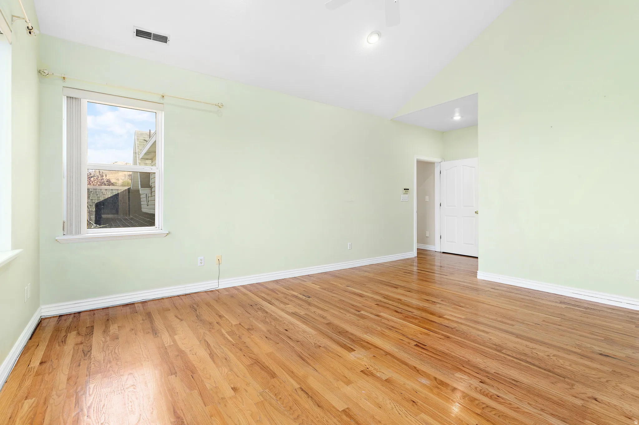 Spacious room featuring wood-finish flooring, vaulted ceiling, and recessed lighting