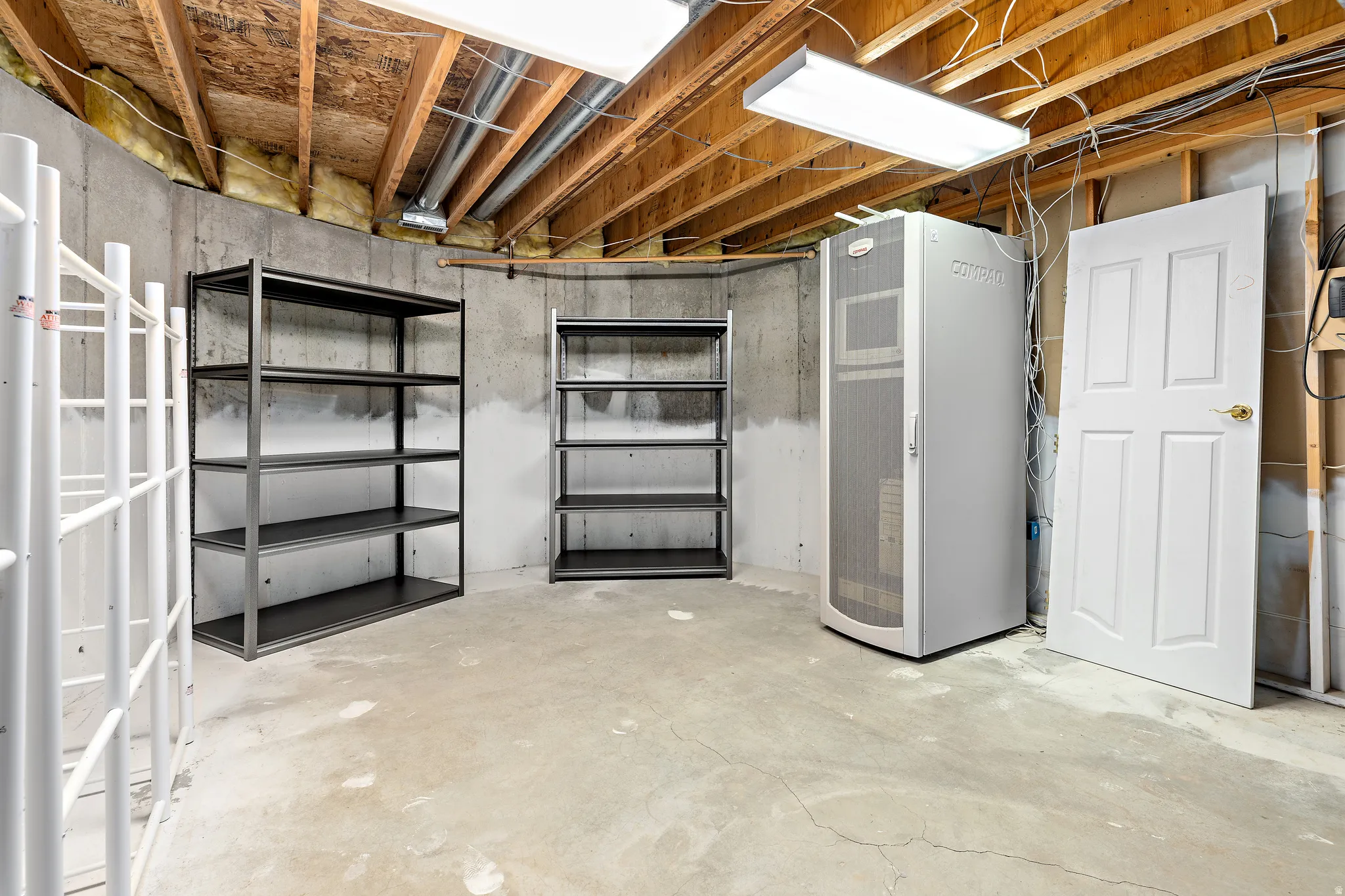 Unfinished basement space featuring exposed wood joists and concrete walls